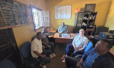 Marie-Louise Norozi and colleagues seated in the commissioner's office, with a chalkboard and a whiteboard on the walls